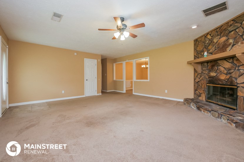 an empty living room with a fireplace and a ceiling fan