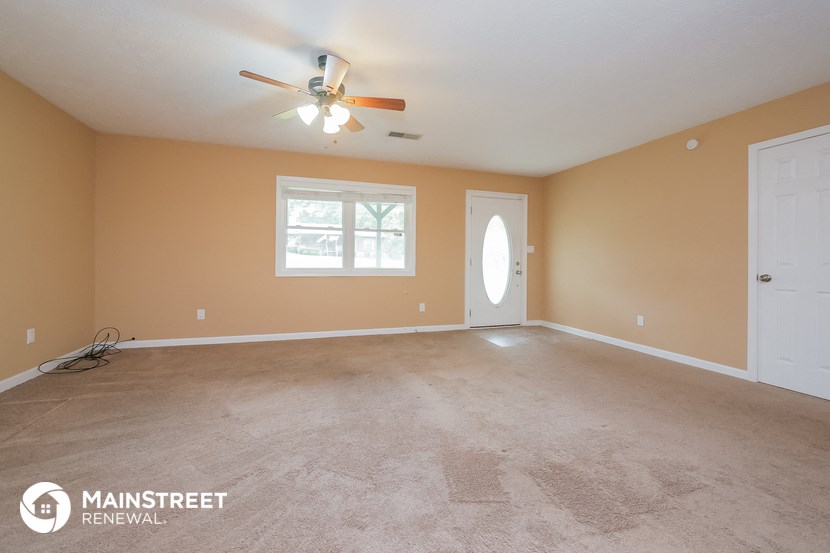 the master bedroom is spacious and clean with carpeting and a ceiling fan
