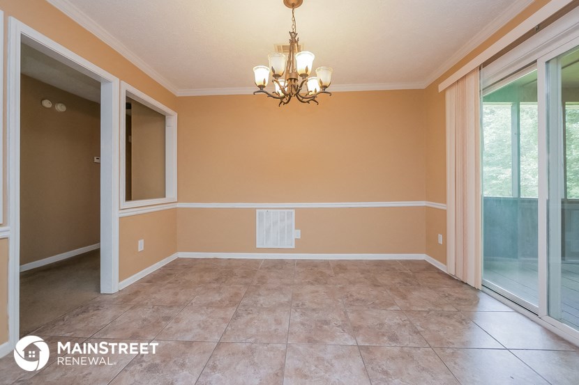 an empty dining room with a chandelier and sliding glass doors