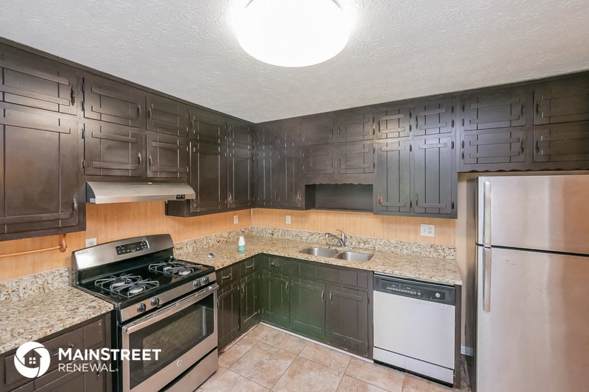 a kitchen with black cabinets and white appliances and granite counter tops