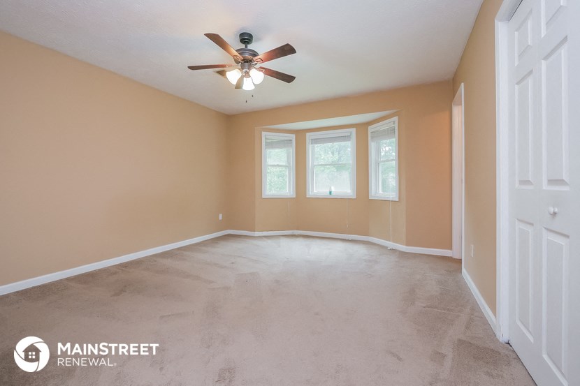 an empty living room with a ceiling fan and a window