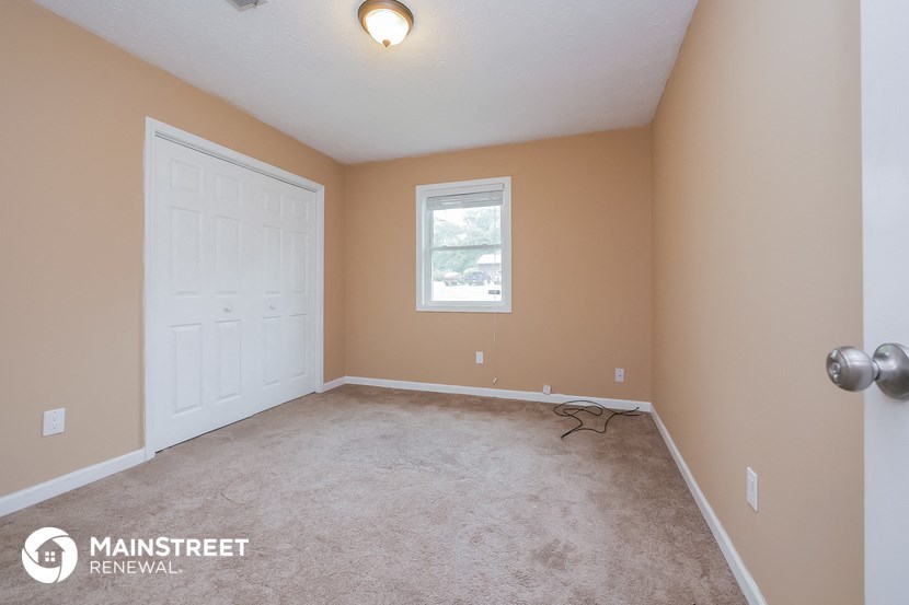 the living room of a house with a white door and carpet