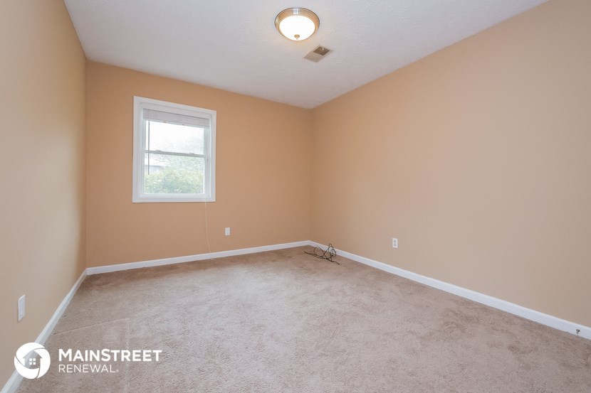 the upstairs bedroom with carpet and a window