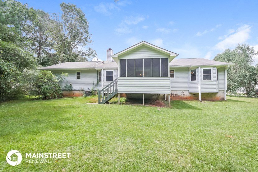 the front of a white house with a lawn and a staircase