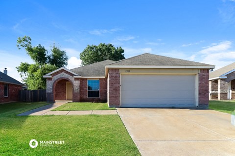 a brick house with a garage and a lawn