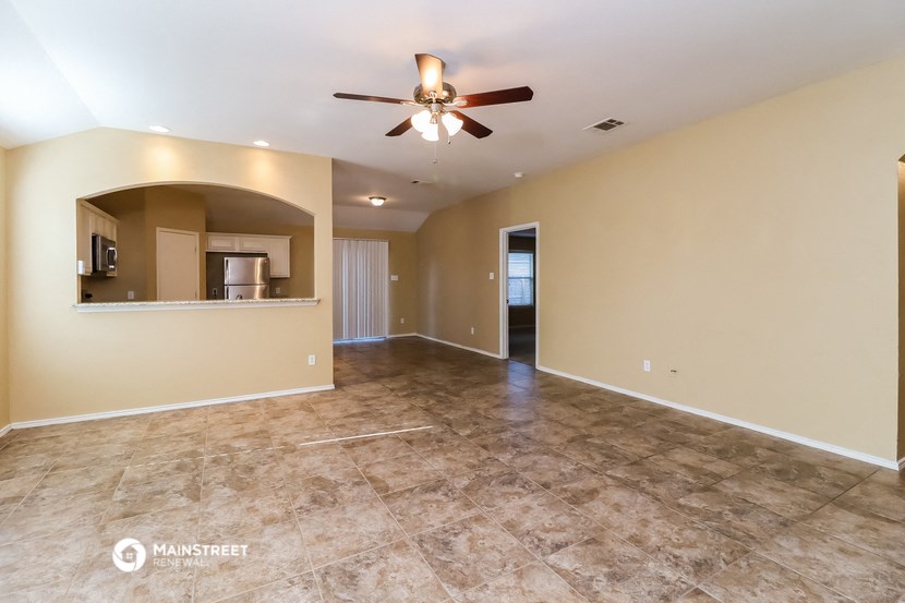 the spacious living room with tile flooring and a ceiling fan