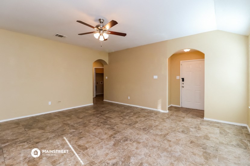 the spacious living room with tile flooring and a ceiling fan