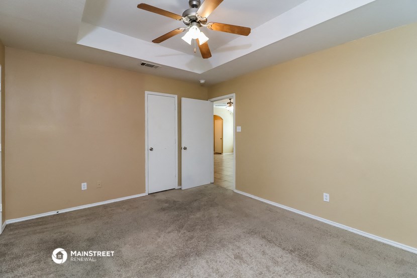 a empty living room with carpet and a ceiling fan