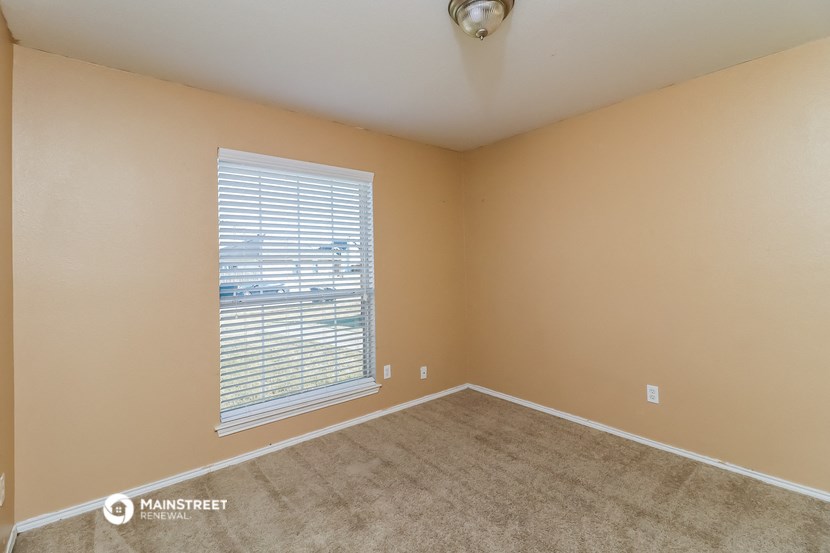 the living room of an empty home with a large window and carpet