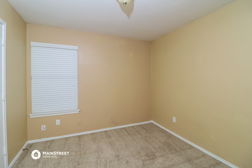 a bedroom with a large window and a carpeted floor