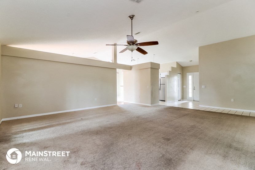 an empty living room with a ceiling fan and white walls