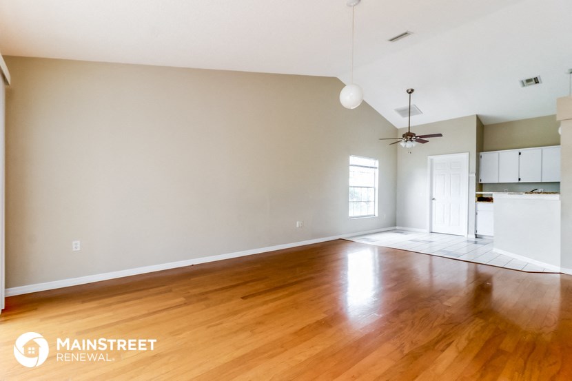 the living room and kitchen of an empty house with wood floors