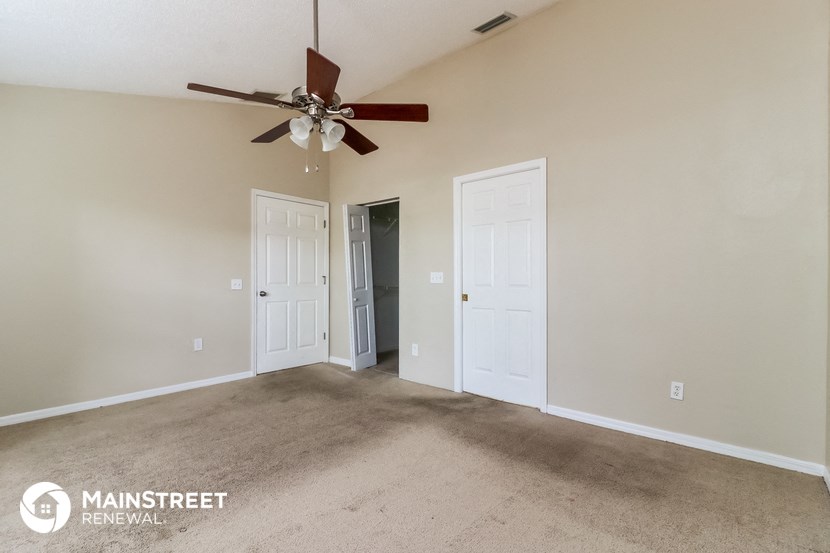 a living room with carpet and a ceiling fan