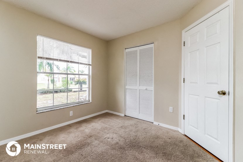 the master bedroom has a large window and carpeted flooring