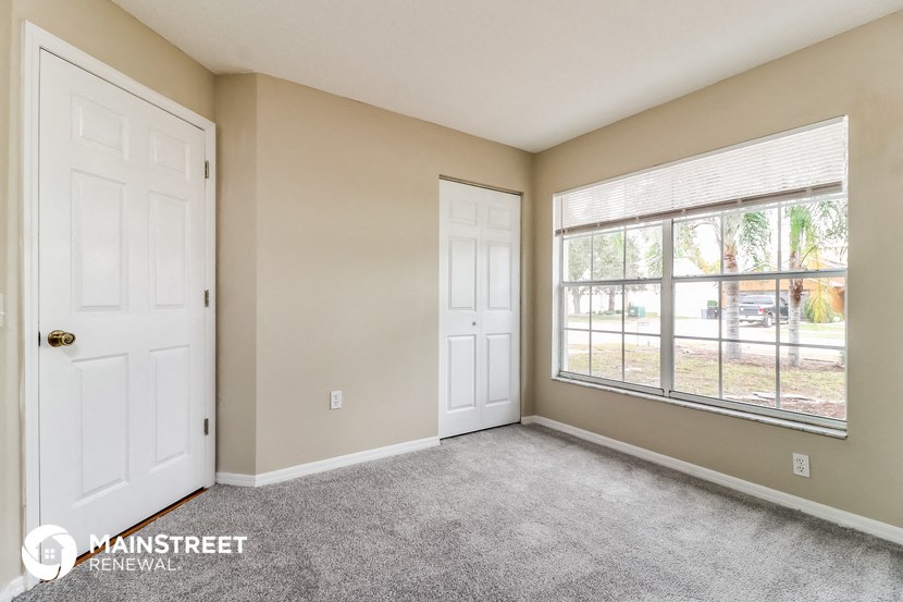 an empty living room with two doors and a window