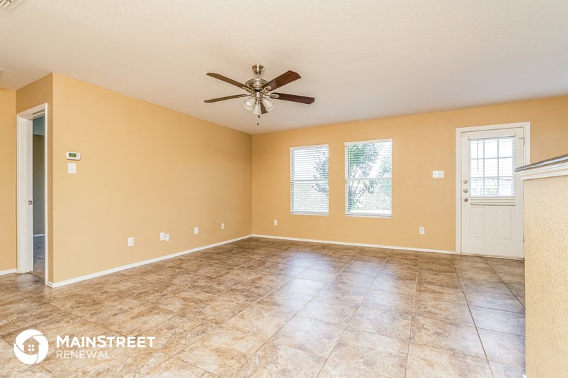 the spacious living room with tile floors and a ceiling fan