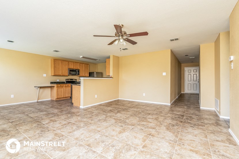 an empty living room and kitchen with a ceiling fan