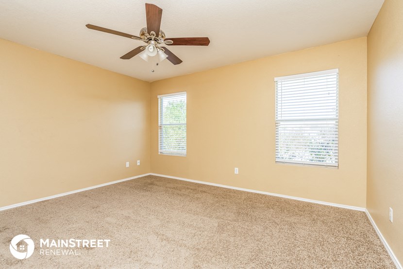 the master bedroom has a carpeted floor and a ceiling fan
