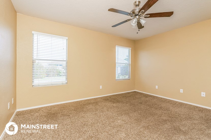 the master bedroom has carpet and a ceiling fan