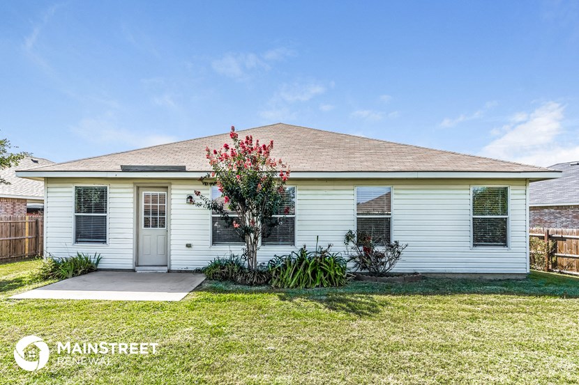 the front of a white house with a lawn and a tree