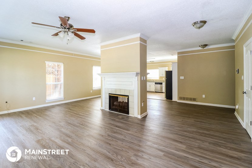 an empty living room with a fireplace and a ceiling fan