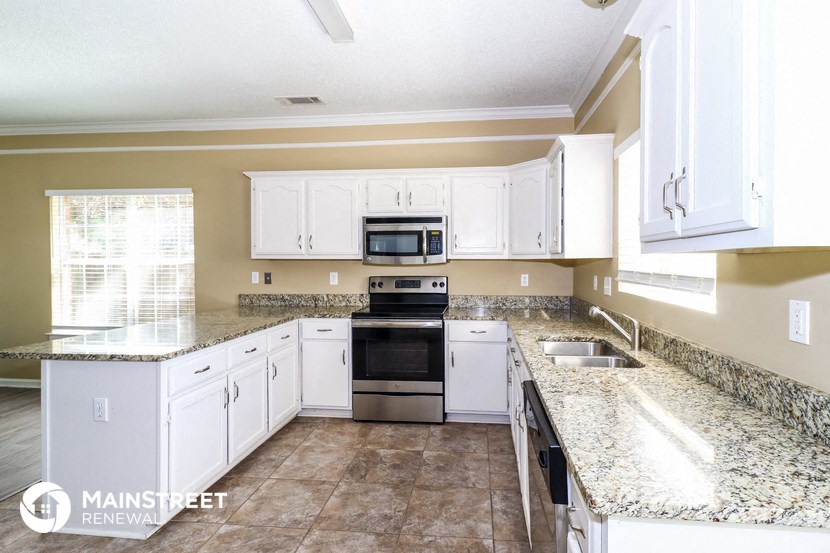 a kitchen with white cabinets and granite counter tops
