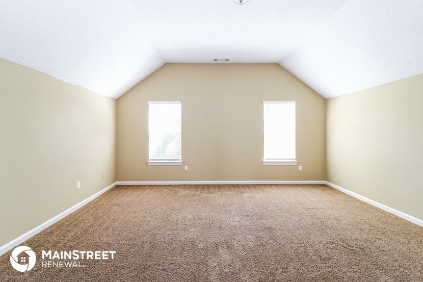 the upstairs bedroom with carpet and two windows