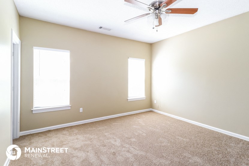 the master bedroom has a carpeted floor and a ceiling fan