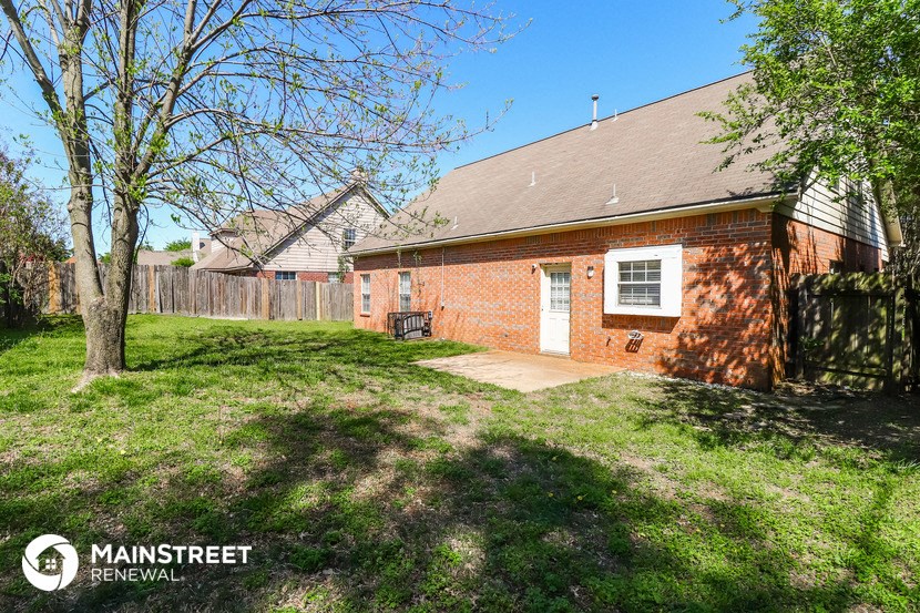 a brick house with a yard and a wooden fence