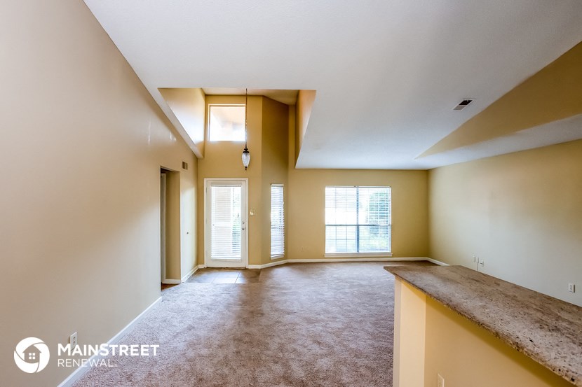the living room and dining area of an empty house with a large window