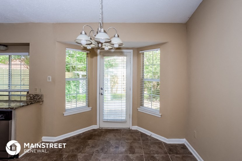 the kitchen and dining room of a home with windows and a chandelier