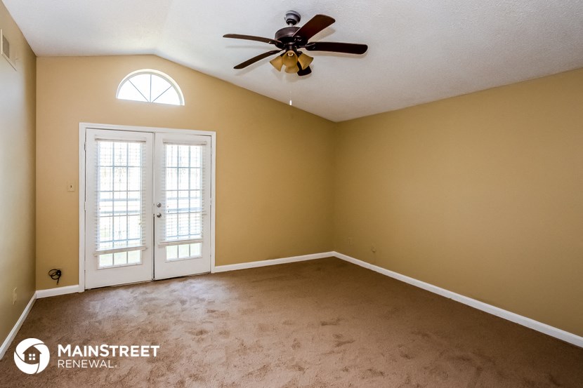 a empty living room with a ceiling fan and doors