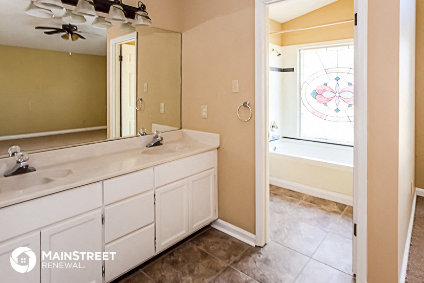 the master bathroom has a large vanity with two sinks and a large mirror