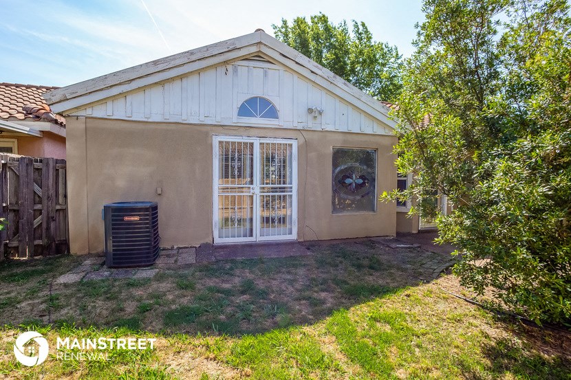 a small tan house with a backyard and a garbage can