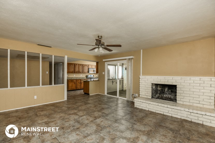 a living room with a brick fireplace and a ceiling fan