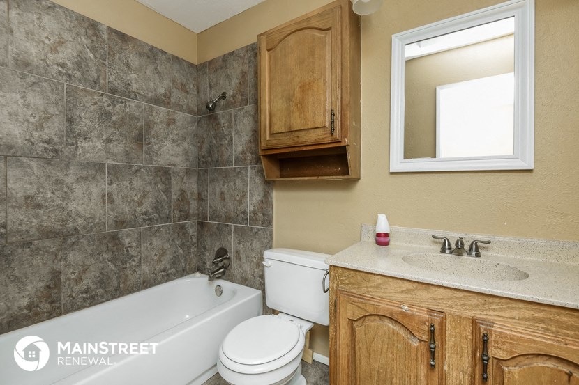 a bathroom with a tub sink and toilet and a mirror