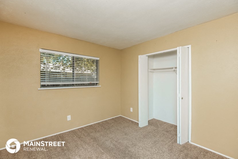 a bedroom with a window and a door to a closet
