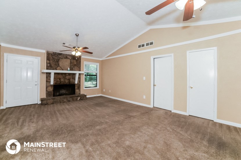 a living room with a fireplace and a ceiling fan