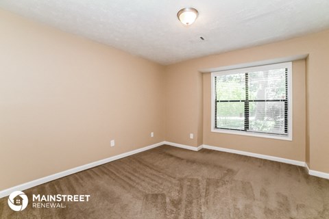 the spacious living room with carpet and a large window