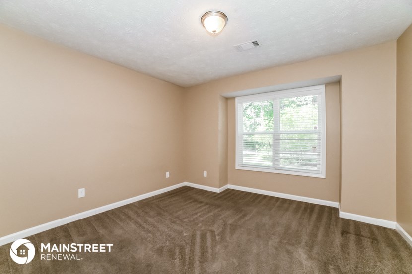 the upstairs bedroom with carpeted flooring and a window