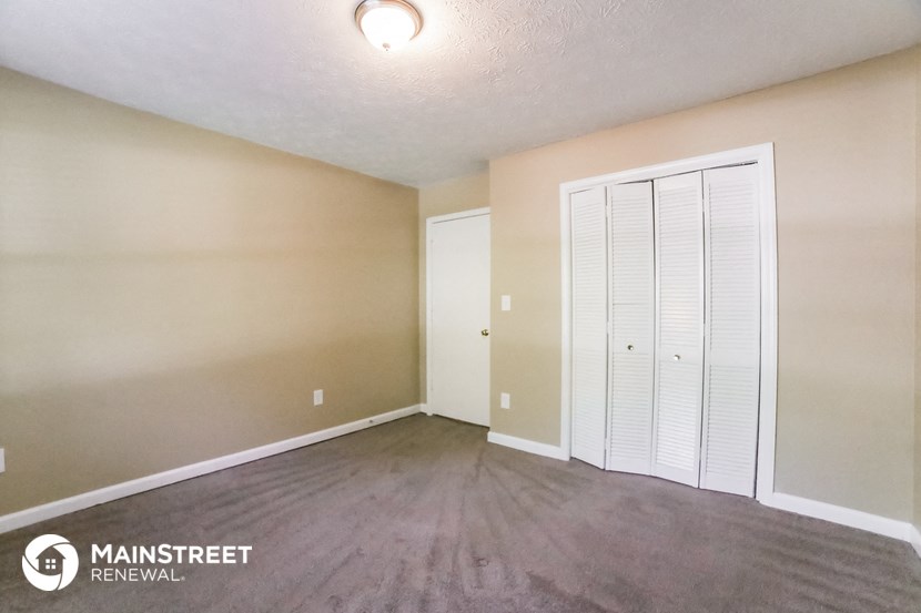 an empty living room with wood flooring and a closet