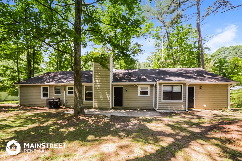 the front of the house with the yard and trees