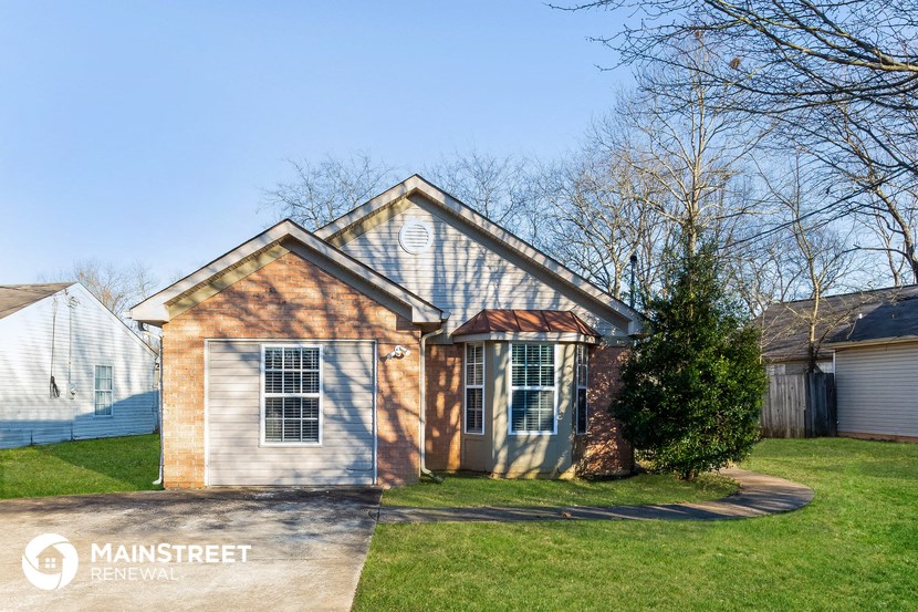 a small brick house with a garage and a tree in the yard