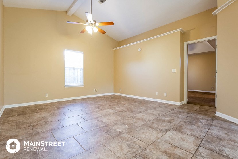the living room of an empty home with a ceiling fan
