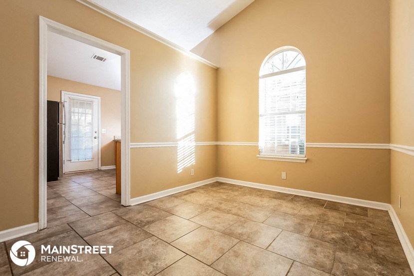 the living room of a home with a large window and tiled floors
