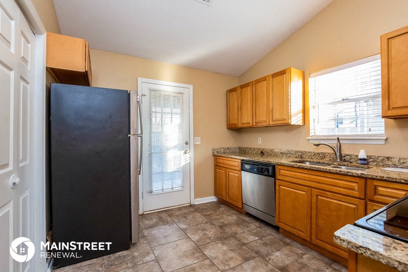 a kitchen with wood cabinets and a refrigerator and a sink