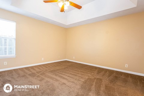 the living room of a new home with carpet and a ceiling fan