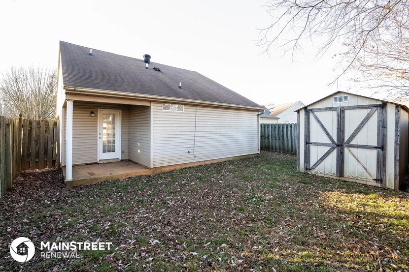 the backyard of a small white house with a garage