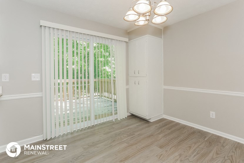 the living room of an apartment with white blinds and a sliding glass door
