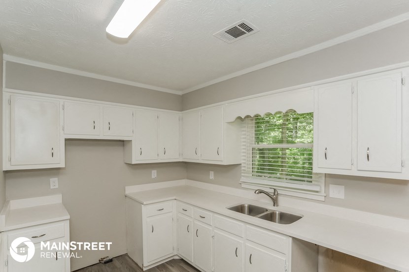 a kitchen with white cabinets and a sink and a window